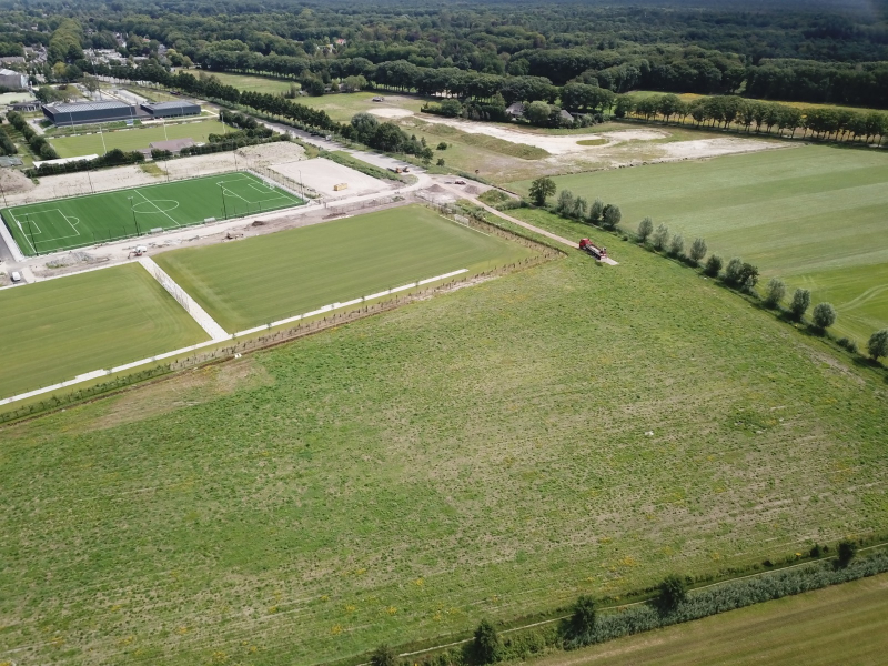 Dronefoto's van rijplaten leggen in een weiland naast een voetbalveld