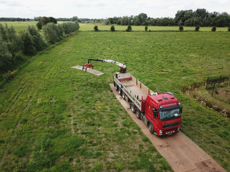 Rijplaten leggen in weiland met kraanwagen van bovenaf